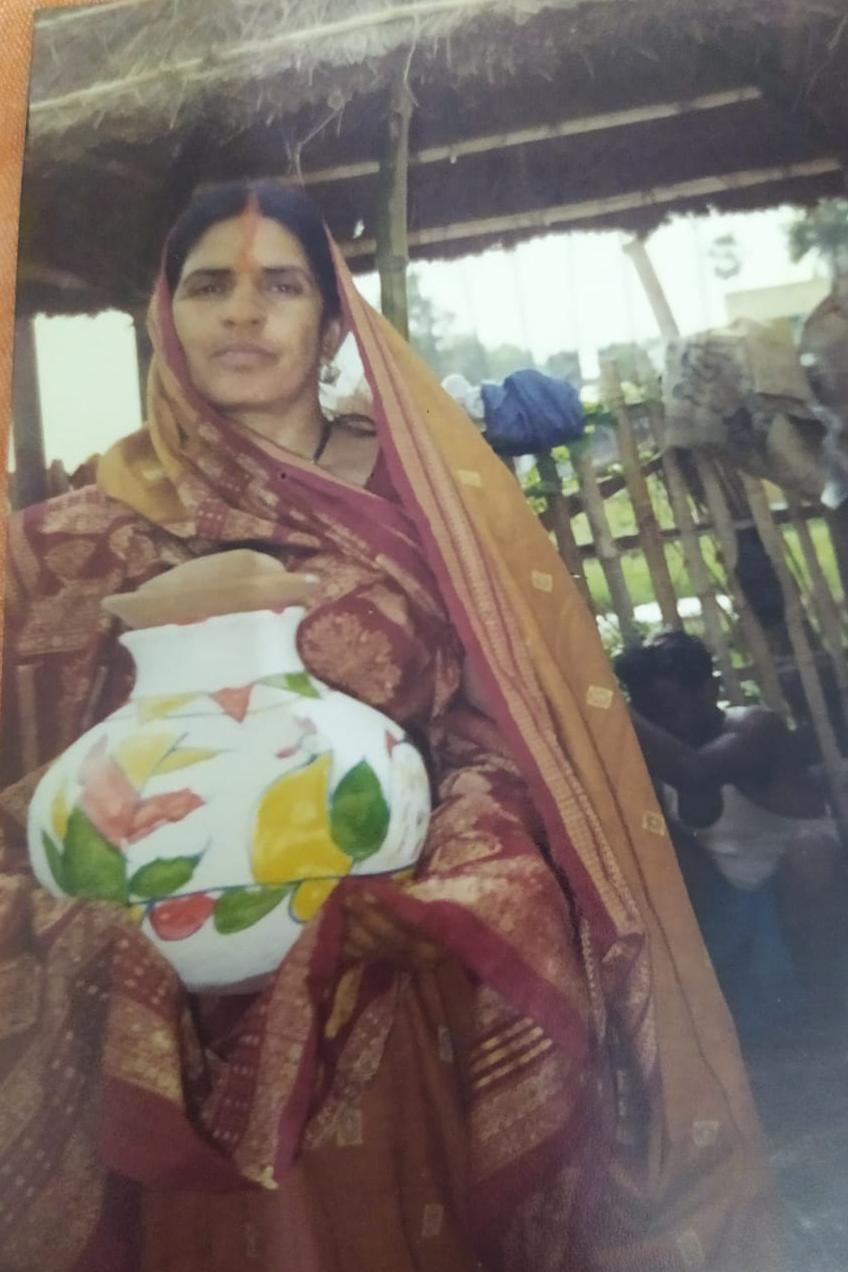 Fula Devi holding a decorated clay pot during her daughter's wedding ceremony.