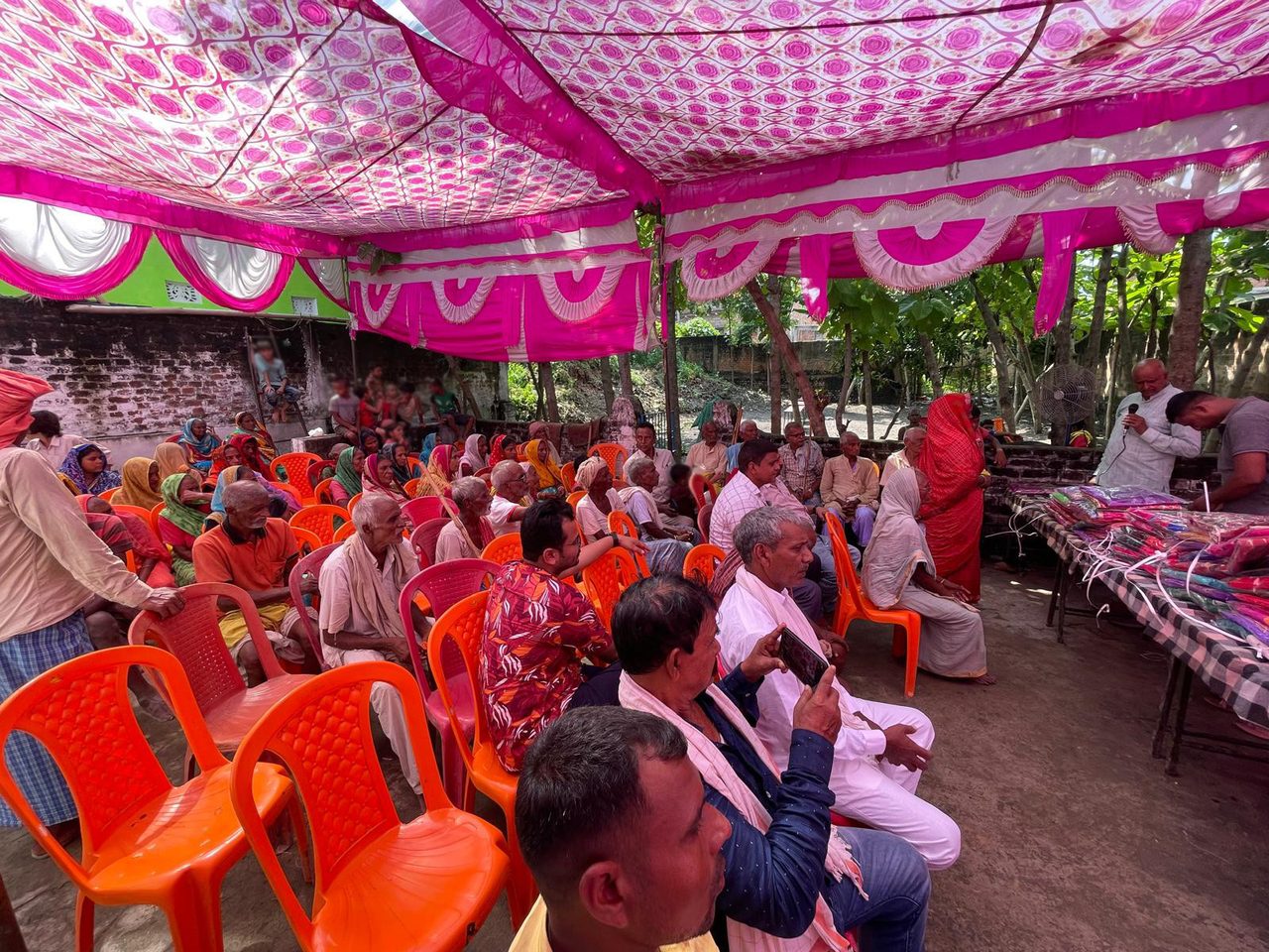 Villagers seated beneath a pink canopy at the 2024 seasonal clothing distribution.