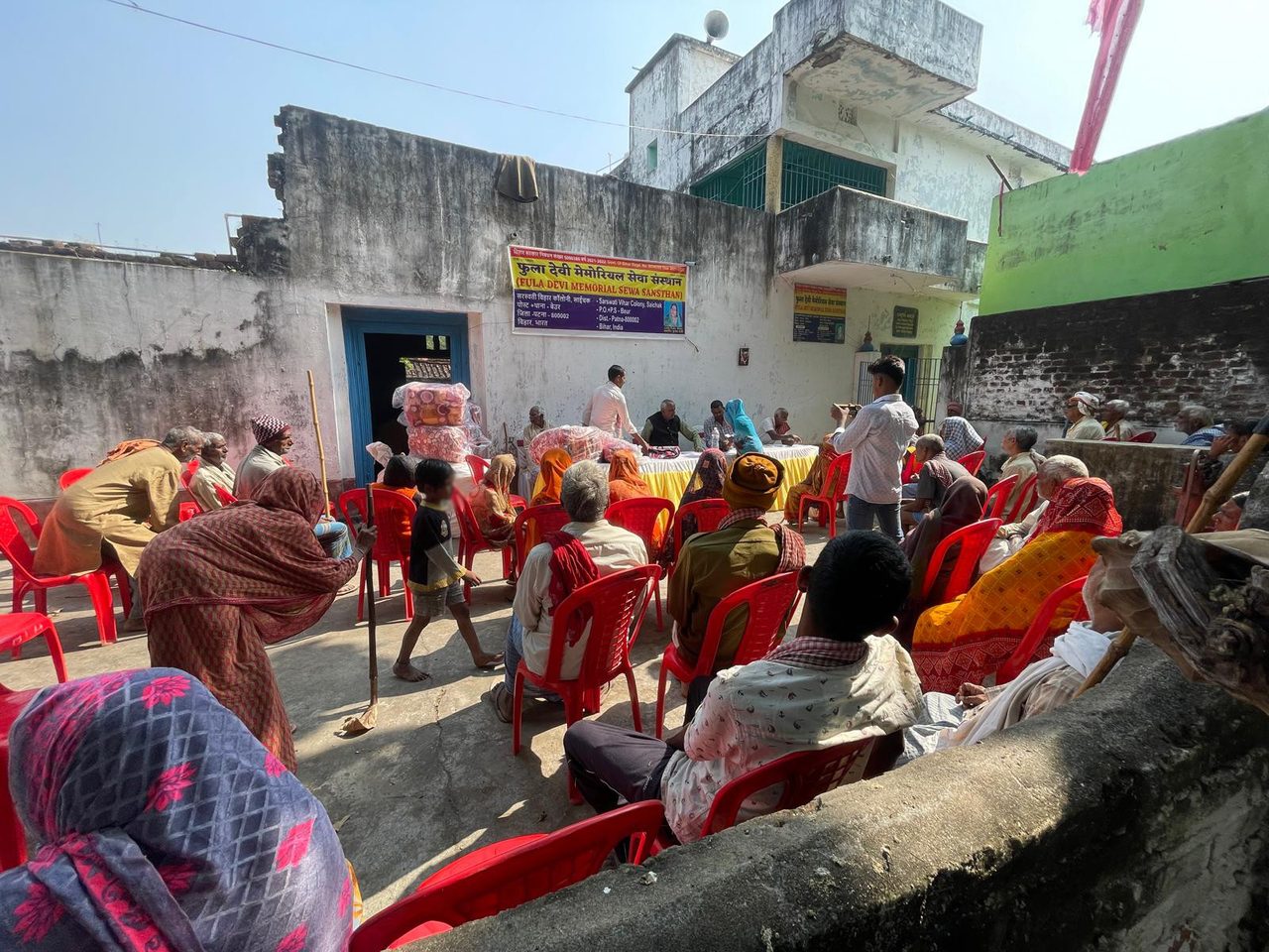 Villagers in a courtyard at the 2025 winter blanket distribution beneath the institution’s banner.
